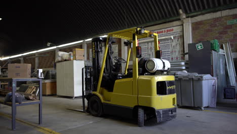 Slow-dolly-in-of-a-yellow-forklift-parked-in-a-warehouse