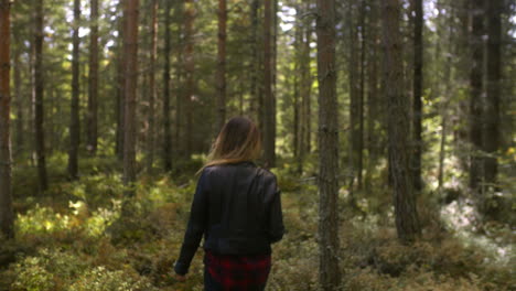 A-woman-wearing-a-leather-jacket-walks-in-a-forest