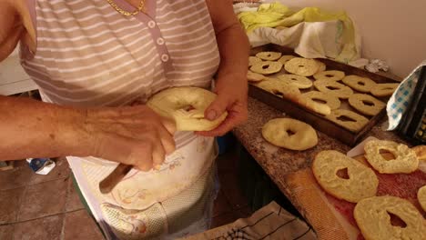 Cutting-bread-with-the-knife-to-make-freselle,-typical-Southern-Italian-hard-bread