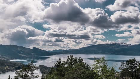 Thick-white-gray-clouds-whirling-and-moving-above-the-calm-blue-water-of-the-Hardanger-fjord