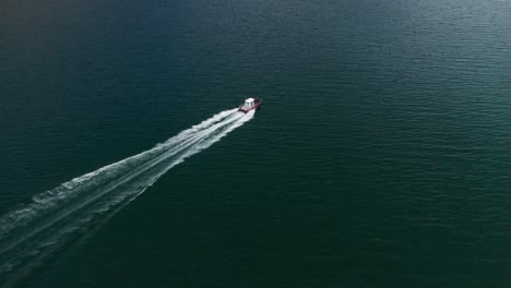 Luftaufnahme-Des-Schnellen-Motorboots,-Das-Auf-Dem-Wasser-Des-Fjords-Fährt-Und-Wellen-Und-Einen-Strom-Weißen-Schaums-Hinter-Sich-Lässt