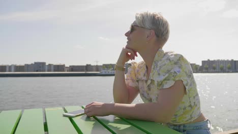 Süße-Junge-Touristenfrau-Beobachtet-Boote-In-Der-Bucht-Und-Sitzt-Im-Sonnenlicht-Auf-Einem-Pier