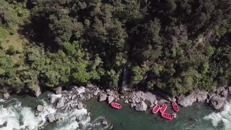 Leuchtend-Rote-Flöße,-Die-Bereit-Sind,-Touristen-Auf-Ein-Wildwasser-Rafting-Erlebnis-In-Neuseeland-Mitzunehmen---Draufsicht
