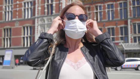 Mujer-Holandesa-Con-Gafas-De-Sol-Puesta-Una-Máscara-Frente-A-La-Estación-Central-De-Amsterdam-Durante-La-Pandemia-Del-Virus-De-La-Corona