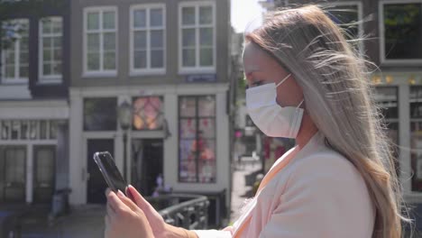 Mujer-Turista-Tomando-Selfie-Usando-Su-Teléfono-Celular-De-Pie-En-El-Puente-Del-Canal-En-Amsterdam,-Países-Bajos-Durante-El-Brote-De-Covid-19