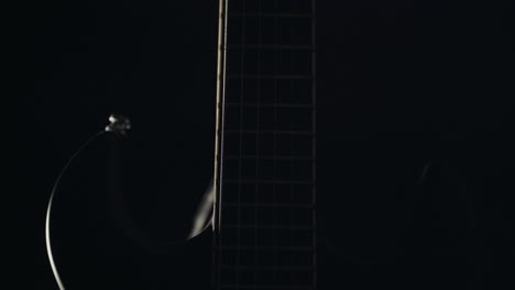Light-slowly-revealing-guitar-in-complete-darkness