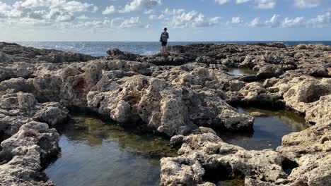 Young-white-traveler-enjoying-sea-waves-hitting-rocky-Malta-coast