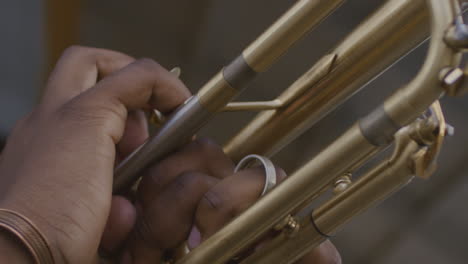 A-black-person's-hands-are-seen-holding-the-body-of-a-brass-trumpet-as-they-play-it