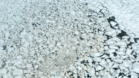 Aerial-fly-over-view-of-cracked-ice-floes-floating-in-the-sea