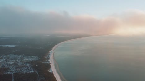 Beautiful-foggy-aerial-view-of-seaside-coastline-in-winter-at-sunrise,-sunset