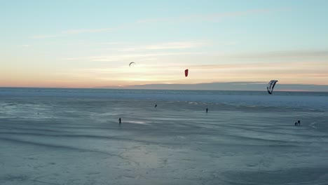 Beautiful-drone-shot-of-kite-boarding-over-frozen-sea-at-sunset