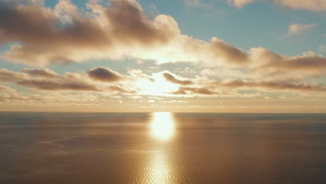 Epic-aerial-view-of-golden-sunset,-sunrise-at-sea-with-strong-reflection