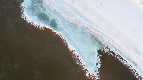 Top-down-view-of-frozen-seaside-coastline-in-winter