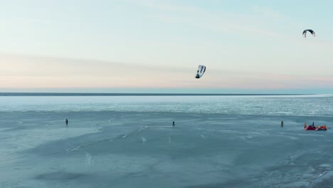 Beautiful-drone-shot-of-kite-boarding-over-frozen-sea-at-dusk