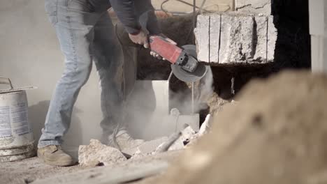 Construction-laborer-using-angle-grinder-to-cut-cement,-concrete,-low-angle-view