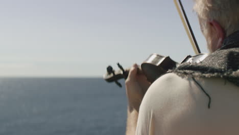 Ein-Mann-Spielt-Geige-Und-Blickt-Aufs-Meer