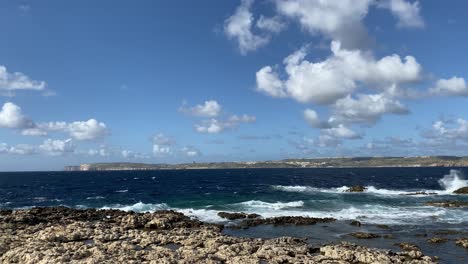Waves-strike-beautiful-rocky-coastline-of-Malta,-Island-of-Gozo-in-background-coast