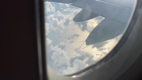 Clouds-cast-shadows-on-open-sea-beyond-the-wind-of-a-traveling-airplane--porthole-view