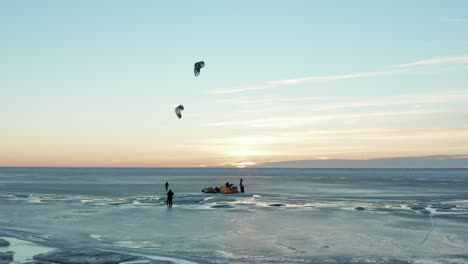 Surreal-beautiful-drone-shot-of-kite-boarding-over-frozen-sea-at-sunset