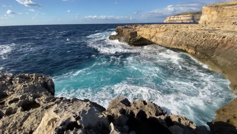 Idyllic-maltese-coastline,-waves-crash-and-erode-shore-near-famous-Blue-hole