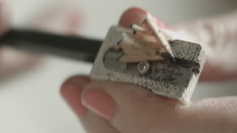 Person-sharpening-a-pencil-in-a-metallic-sharpener