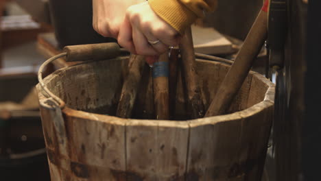 A-rag-is-dipped-and-the-water-in-a-wood-bucket-filled-with-tools-and-then-wrung-out