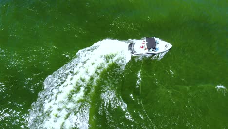 Aerial-top-down-vertical-view-of-tourist-performing-stunts-during-water-skiing