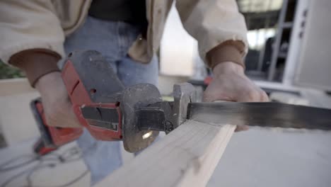 Slow-motion-close-up,-cordless-reciprocating-straight-saw-cutting-plank