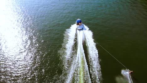 Aerial-drone-footage-of-tourist-enjoying-water-skiing,-tied-behind-high-speed-motor-boat