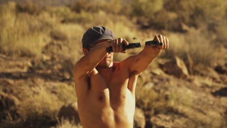 Close-up-front-view-of-a-young-shirtless-American-boy-in-sunglasses-firing-two-handguns-rapidly