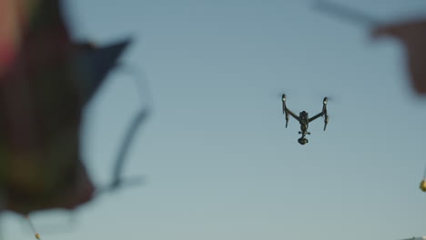 Two-people-standing-with-a-drone-in-the-sky-with-trees-in-the-background