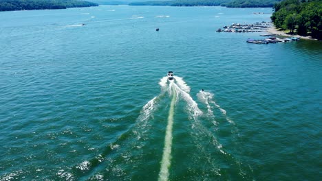 Birds-eye-view-of-tourists-enjoying-water-skiing,-tied-behind-high-speed-motor-boat