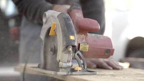 Close-up-shot-of-red-color-circular-saw-cutting-wood-with-sawdust-flying