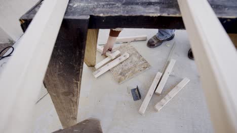 Male-hands-pick-up-wood-scraps-or-off-cuts-from-workshop-floor