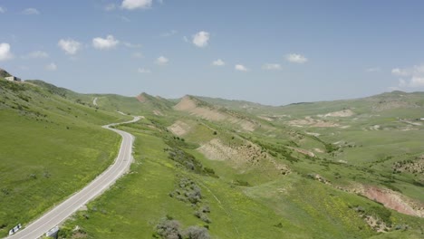 Aerial-view-flying-over-mountainous-terrain-along-curvy-empty-road