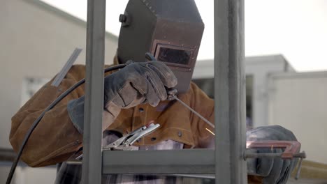 Industry-worker-welding-metal-object-in-static-tripod-shot