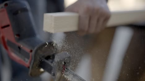 Close-up-slow-motion-shot,-cordless-reciprocating-saw-cuts-through-plank-or-batten