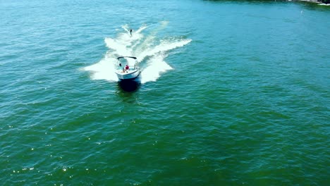 Luftaufnahme-Eines-Hochgeschwindigkeits-Motorboots,-Das-Einen-Wasserskifahrer-Zieht