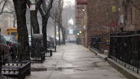 Snow-tumbling-down-on-cold-winter-Brooklyn-street,-in-New-York---Long-medium-shot