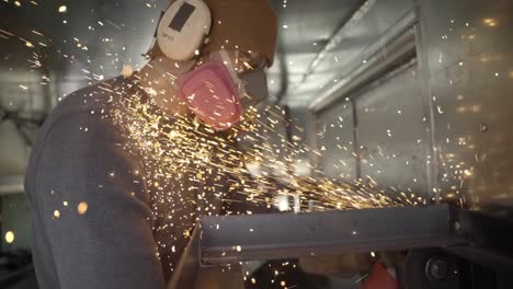 Sparks-erupt-as-skilled-worker-cuts-metal-with-angle-grinder-in-workshop--slow-mo