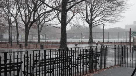 Cold-snowfall-soaking-a-city-park-on-a-grey,-eerie-day-in-Brooklyn,-New-York---Medium-static-shot