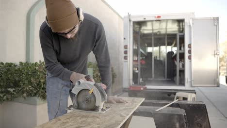 Carpenter-using-circular-saw-to-cut-wood-plank-or-board-outside
