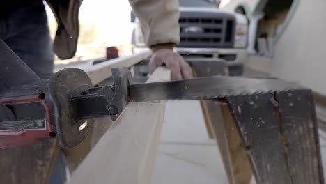 Closeup-of-electric-straight-blade-saw-cutting-into-wood-plank,-slow-motion