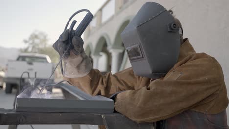 Person-in-welding-gear-uses-arc-welder-to-fuse-corner-of-angle-iron--slow-mo