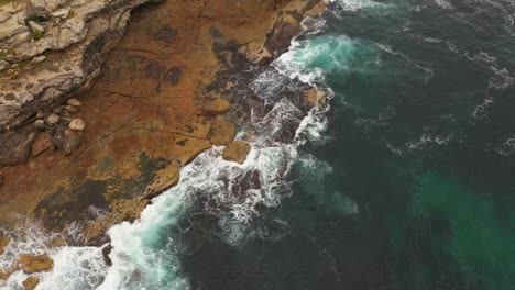 Aerial-view-moving-north-to-south-of-Maroubra-Beach-north-headland-with-unrecognisable-fisherman-on-rocks