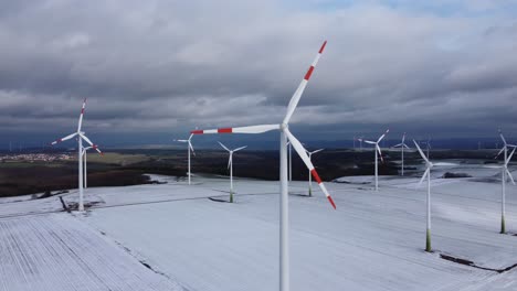 Aerial-orbiting-view-of-a-wind-farm-in-rural-winter-landscape-during-cloudy-day-outdoors-in-nature