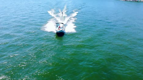 Backward-moving-aerial-showing-tourist-tied-behind-high-speed-motor-boat-and-enjoying-water-skiing