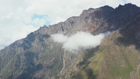 Luftdrohnenansicht-Nähert-Sich-Einer-Massiven-Bergkette-Und-Einer-Wolke-In-Der-Mitte-Der-Aufnahme