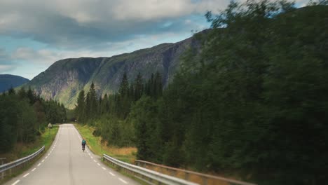 A-lone-cyclist-on-the-narrow-country-road-surrounded-by-pine-forest
