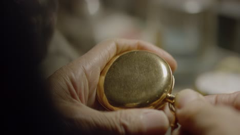 Elderly-person-examines-gold-pocket-watch